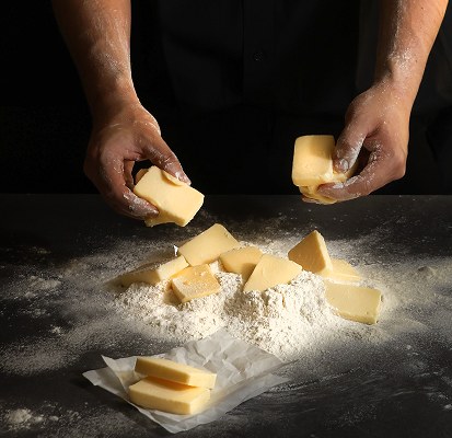 Hands shaping butter into flour
